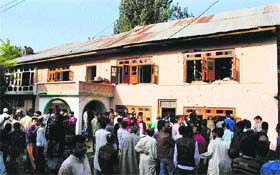 Locals gather outside the bullet-ridden house after an encounter between security forces and a Lashkar militant at Ahmad Nagar on the outskirts of Srinagar on Thursday