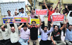 Members of the Kashmiri Migrant Relief Holders and overaged youth protest in support of their demands outside the relief commissioners office in Jammu on Friday. 