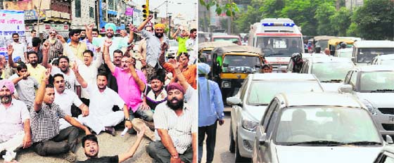 Residents of Transport Nagar stage a dharna in front of the MC office; and (right) an ambulance stuck in a traffic jam during the protest in Jalandhar on Friday.