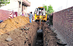 A JCB machine digging a trench to lay a sewerage pipe near the under-construction mall in Bathinda