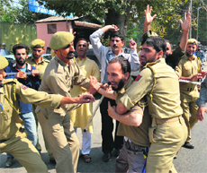 Government employees shout slogans as they are detained by police during a protest outside the Legislative Assembly in Srinagar on Saturday.