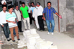 Residents show a pile of interlocking tiles that the MCB workers left behind in the middle of the road after the work was stopped midway