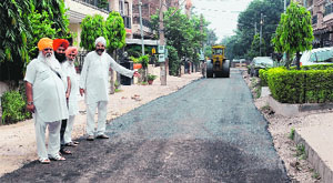 Residents show a road being carpeted in Phase XI, Mohali, on Monday. 