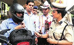 Deputy Commissioner of Police (Traffic) Bharti Arora gives a flower to a motorcyclist for obeying traffic rules at Iffco Chowk in Gurgaon on Wednesday