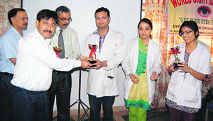 Dr Ramesh Bharti, Officiating Principal, DRPGMC, Tanda, gives away prizes to winners on World Sight Day in the college on Thursday.