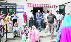 Attendants wait outside a locked gate of the emergency ward as a portion of the ceiling of the ward collapsed in Government Medical College & Hospital in Jammu on Thursday