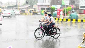 Boys ride on their bicycles during the rain in Amritsar on Friday.