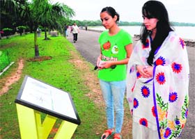 Visitors read a plaque installed at Sukhna Lake