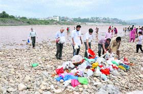 Volunteers collect waste material from Tawi river in Jammu on Saturday