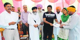 J Ganesan, Deputy Commissioner, gives away a certificate of 100-yard plot to a woman at Trilokewala in Sirsa on Saturday.
