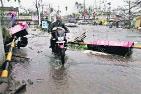 A motorcyclist rides past fallen traffic signal poles in Berhampur on Sunday