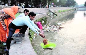 People immerse leftovers of the Navratri Puja in Sirhind canal in Bathinda on Monday.