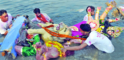 Devotees immerse an Idol of Goddess Durga in the Yamuna in New Delhi on Monday. Tribune photo: Manas Ranjan Bhui 