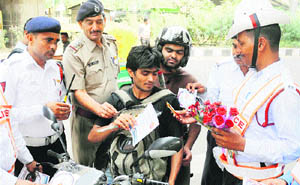 The traffic police gives flowers, biscuits, chocolates and pamphlets to commuters obeying traffic rules at IFFCO chowk in Gurgaon.