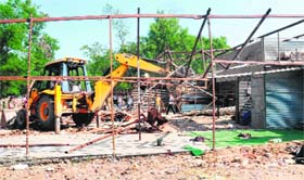 A JCB machine pulls down illegal structures during a demolition drive at the Sector 42 furniture market in Chandigarh on Tuesday.
