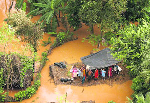 People wait for relief material on the top of a thatch in a flooded locality after heavy rain in the aftermath of Cyclone Phailin in Balasore on Monday.