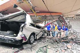 Residents inspect a car after a concrete block fell on it during an earthquake in Cebu city, central Philippines, on Tuesday