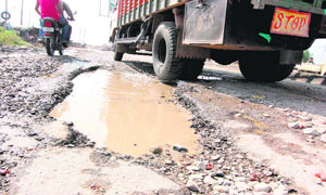 A newly recarpeted road is filled with potholes in Haridwar, posing probems for commuters. 
