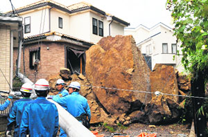 A house and an electric pole smashed by large rocks from a collapsed slope caused by heavy rain in Tokyo on Wednesday.