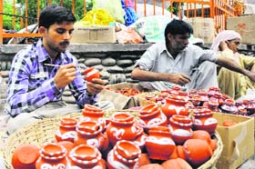 A man decorates earthen pots at Purani Mandi in Jammu on Thursday