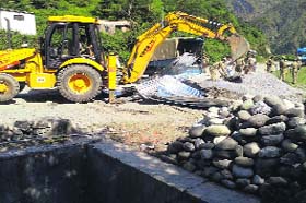 Officials of the district administration demolish the illegal structure on a disputed land at Gujjar Khotia village in Talwara area of Reasi district on Thursday