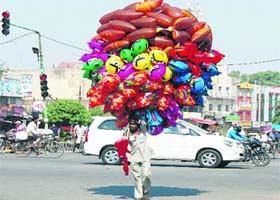 The merchant of colours: A balloon seller crosses a road in Amritsar on Sunday