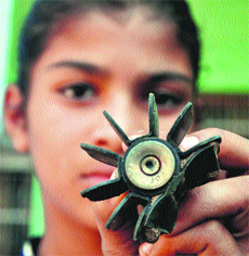 A girl on Sunday shows the tailfin of a 82-mm mortar fired by Pakistan Rangers on October 18 -19 night in Suchetgarh-Kulian village in Samba district. 