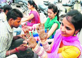 Gearing up for occasion: Artists apply mehndi on the hands of women on the eve of Karva Chauth in Amritsar on Monday
