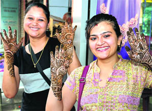 Girls show the pattern of henna applied on their hands on the eve of Karva Chauth in Bathinda on Monday.