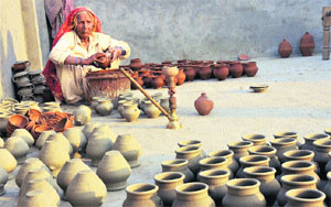 An old woman colours earthen pots on the eve of Karva Chauth festival in Karnal