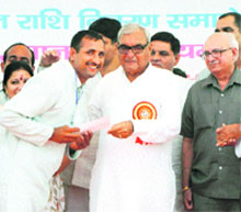 Chief Minister Bhupinder Singh Hooda gives a cheque to an owner of a murrah buffalo in Jhajjar.