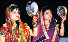 Women look at the moon through the sieve before ending their fast on Karva Chauth in Bathinda on Tuesday