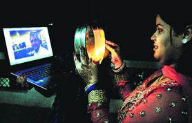 Yamini Dubey, wife of an NRI IT professional, looks at her husband through a web cam on a laptop while performing Karva Chauth rituals in Jalandhar on Tuesday. 