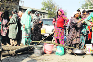 Women block the main road in protest against shortage of drinking water at Newa in Pulwama district on Tuesday.