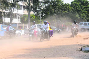Commuters move through a dusty road near the site of a multi-level parking project in Sector 17, Chandigarh.