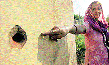 A villager on Wednesday points to the bullet mark on a wall of her house left by Pakistani firing in Pindi Charakan village in the Arnia sub-sector of the Jammu region