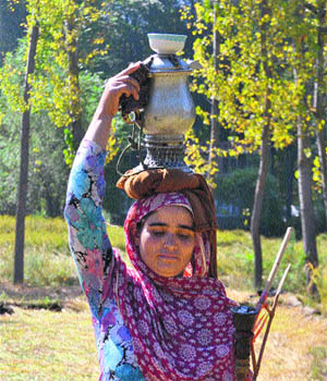 A woman carries a Samovar full of traditional salt tea in Anantnag on Wednesday.