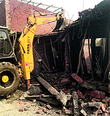 An earthmoving machine demolishes a structure at Jawaddi in Ludhiana on Wednesday