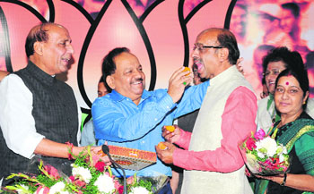 BJPs chief ministerial candidate for Delhi Harsh Vardhan offers sweets to Delhi BJP chief Vijay Goel as party chief Rajnath Singh and senior leader Sushma Swaraj look on in New Delhi on Wednesday.