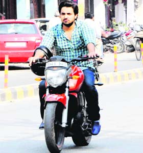 Not caring two hoots about following traffic norms, a youth rides a motorcycle hanging a helmet in his arm and not wearing it on head in Amritsar