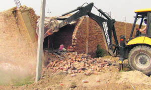 An unauthorised construction being demolished with a JCB machine on the Firozpur Bangar- Auchandi border road in Sonepat district on Thursday. 