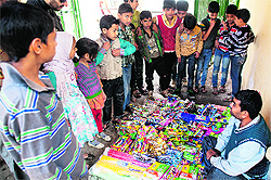 Children gather around a vendor selling toys on the roadside in the Old City, Srinagar