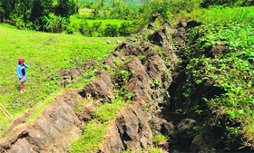 A man looks at a huge crack, which created a rock wall stretching for miles through farmlands, in Anonang village of the Philippines.