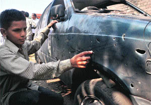A boy shows marks left on a car after a mortar explosion in the Garkhal area in Jammu district on Friday. 