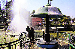 Girls watch a fountain at a park in Srinagar on Saturday