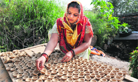 A potter dries earthen lamps in bright sunlight ahead of Diwali festival, in Jammu on Sunday.