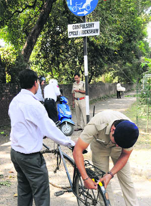 A policeman pastes a reflector on a bicycle, while the other two challan a two-wheeler rider for using the lane meant for cycles at Sector 20 in Chandigarh on Monday.