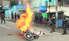 A policeman tries to douse the flames on a motorcycle on the outskirts of Dhaka on Monday. 