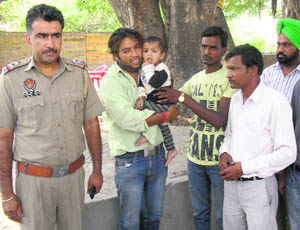 Volunteers of the Sahara Jan Sewa hand over the one-and-a-half-year-old child, who was rescued from a GNDTP lake, to his father on Tuesday. 