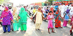 Family members of a youth, who died of poisoning, make a human chain to block vehicular traffic in Sirsa on Tuesday
